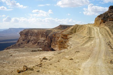 dirt road on the edge of crater ramon in negev desert. israel                               