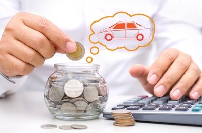 businessman hand putting money coins into glass piggy bank for buy car