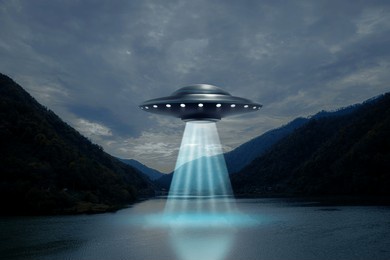 alien spaceship emitting light beam in air over lake. ufo