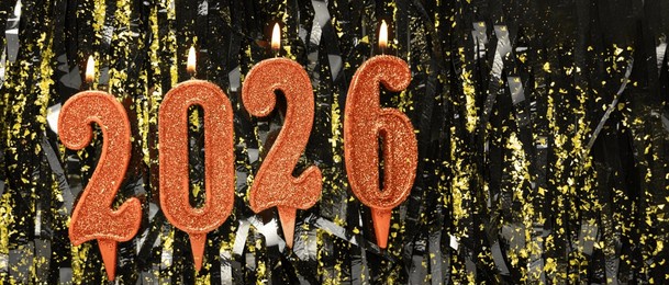 candles number 2026 red colored with confetti on a dark background. new year composition. banner. copy space
