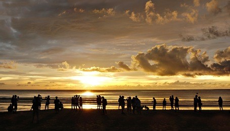 sillhouette of a bunch of beach goers enjoying the sunset over tanjung aru beach, kota kinabalu, sabah.