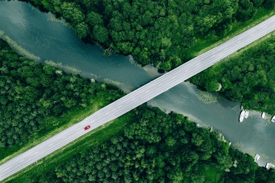 aerial view of bridge road with car over blue river and green summer woods in finland