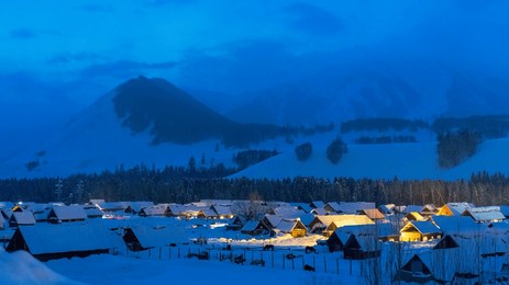 village under snowy mountains at night
