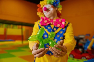 cute green balloon dog toy in hand of funny clown