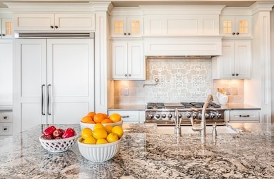 kitchen interior detail in new luxury home with island, sink, cabinets, and bowls of fruit