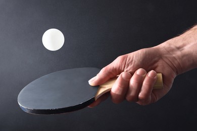 detail of ping pong player hitting a white ball with the black rubber part of a paddle on black isolated background. front view.
