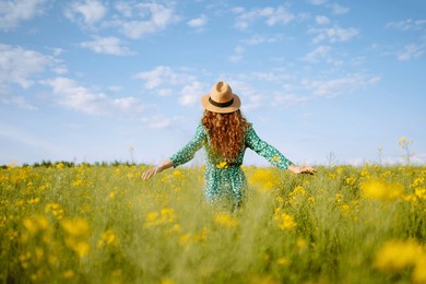 young woman walks through a field of yellow flowers. fashion, lifestyle, travel and vacations concept.