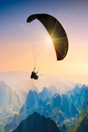 paraglide silhouette over mountain peaks.