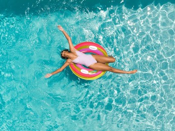 teenage biracial girl enjoys a sunny day in the pool. she relaxes on a colorful float, embracing the joy of summer.