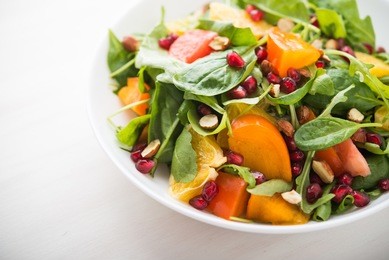 fresh salad with fruits and greens on white wooden background close up. healthy food.