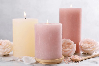 spa composition with burning candles, flowers and sea salt on white marble table