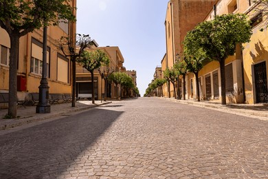 main pedestrian street of a typical sicilian village in the early afternoon sun; no people, a small dog 