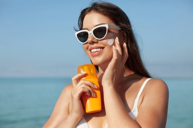woman smile applying sun cream on face. skincare. body sun protection. sunscreen. female in hat smear moisturizing lotion on skin