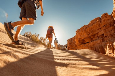 group of tourists with small backpacks walks in sunset desert