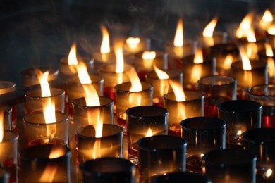 detail of many red votive candles light inside chinese temple. rows of votive candles in glass with shallow depth of field, blurred of candles, red candle is kindle a fire in glass, focus and blur.