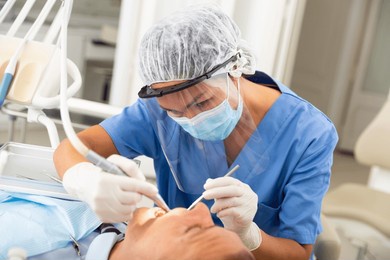 dentist professional filling teeth for man patient sitting in medical chair