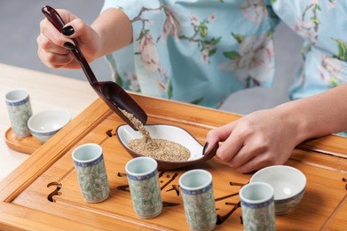 oriental dry tea. closeup portrait of young beautiful japanese woman in traditional kimono getting ready for tea ceremony with tea tools 