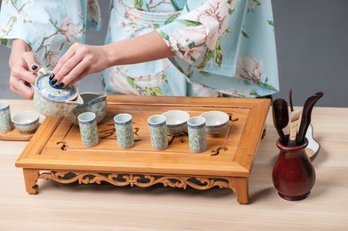 zen tea setting. closeup portrait of tea ceremony performed with tea tools on wooden table by beautiful japanese woman 