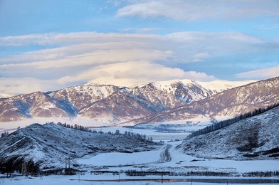cold snowy mountain landscape at sunset. lenticular clouds. panoramic view of snowy mountain peaks and slopes of north chuyskiy ridge at sunset. russia, siberia, altai mountains. 