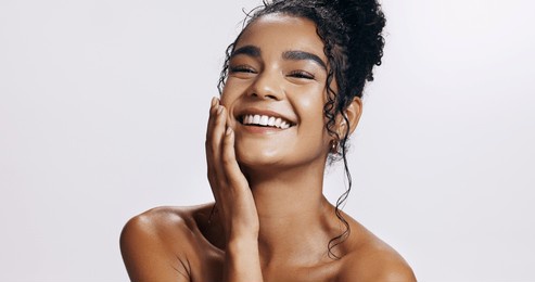 studio, shine and portrait of woman, touch and treatment of skincare, soft and glow of body in results. pink background, face and proud for skin, dermatology and cosmetics for person and hand