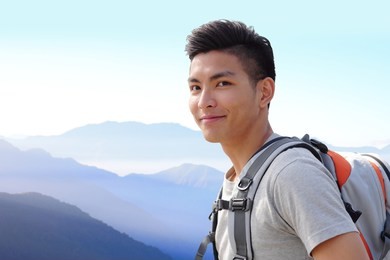 successful man mountain hiker with backpack on the top of mountains. asian