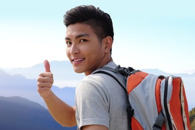 successful man mountain hiker with backpack on the top of mountains. asian