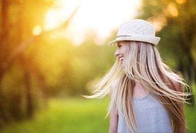 attractive young woman enjoying her time outside in park with sunset in background.