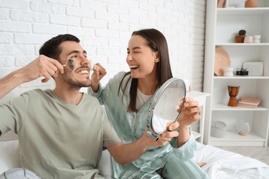 young loving couple massaging their faces with tools in bedroom