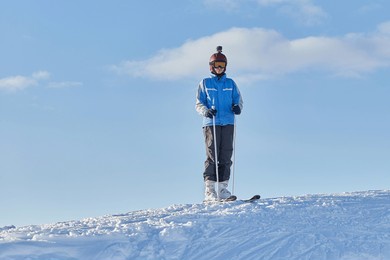 female skier standing on the top of the snowy slopes, sunny day