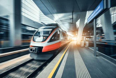 high-speed orange passenger train moving at railway station platform at sunset. train station. modern railway transportation concept with blurred motion effect. railroad. commercial transport