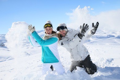 couple in snowy mountain doing snowballs fight