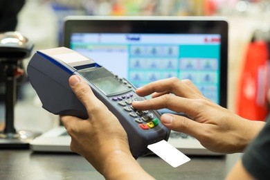 man's hand with credit card swipe through terminal for sale in store