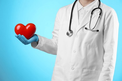 doctor with red heart on light blue background, closeup