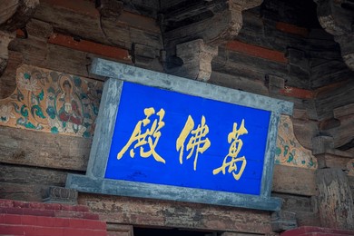 horizontal inscribed board in zhenguo temple, a large buddhist temple in the shanxi province of china. part of unesco world heritage site. the text in chinese: "ten-thousand buddha hall“. 