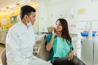 photo of asian female patient explaining her dentist that she has pain