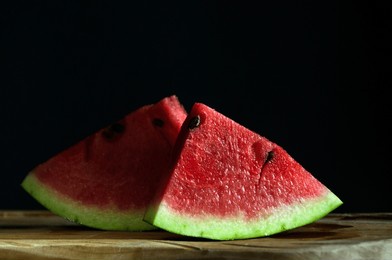 two portioned pieces of fresh watermelon with seeds on a black background