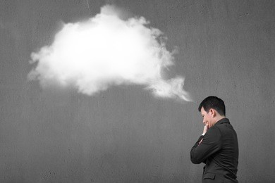 businessman thinking about white cloud thought bubble above his head with concrete wall background
