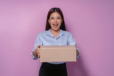excited young woman holding a package, happy with fast delivery service, purple background, online shopping satisfaction