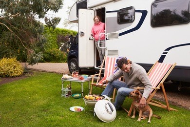 couple in van enjoying barbeque on camping holiday  