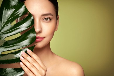close up woman face with green exotic leaf. skin care beauty treatments concept. model with clean, health skin of face. monstera leaves