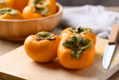 ripe persimmon fruit on cutting wooden board with knife