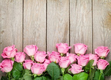 valentines day background with pink roses over wooden table. top view with copy space