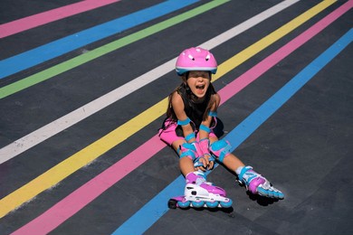 a hysterical girl screams while sitting on the track of a roller rink after falling from roller skates