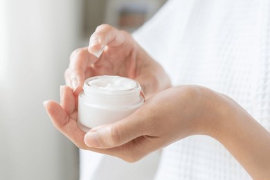 health care, beauty asian young woman in bathrobe, towel after shower bath, spa relax at home, use finger putting take out moisturizer cream from jar. skin body moisturizing lotion, routine in morning
