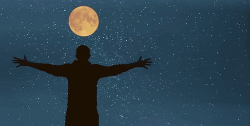 back, rear view of man raising hands on top of a mountain. starry night sky. goals and achievements concept. happy man with hands up enjoying well being. milky way. star night. full moon above head