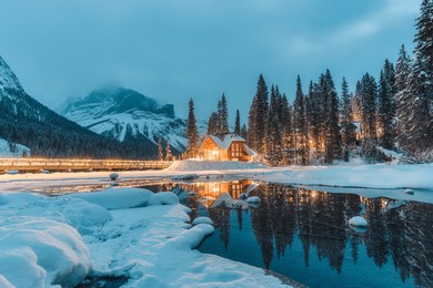 beautiful winter scene of wooden lodge glowing on emerald lake and pine forest at yoho national park, british columbia, canada