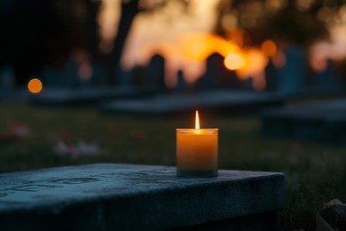 a single, melting candle placed on a cemetery stone, set against the backdrop of a vibrant sunset