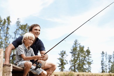 father, boy and fishing by lake for teaching, vacation and travel together in summer with gear on dock. dad, son and catch fish in nature for learning, holiday and development while bonding with line