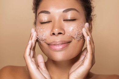 close up portrait of african american young woman applying a scrub skin care mask on her face. skincare exfoliating dermatology procedure 