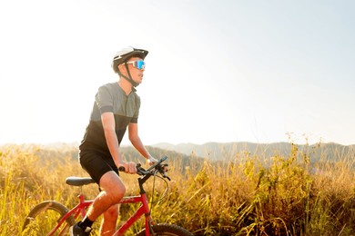 cyclist riding a bike on a trail on a sunny day. he is wearing cycling gear and apparel. inspirational image of a healthy lifestyle through cycling